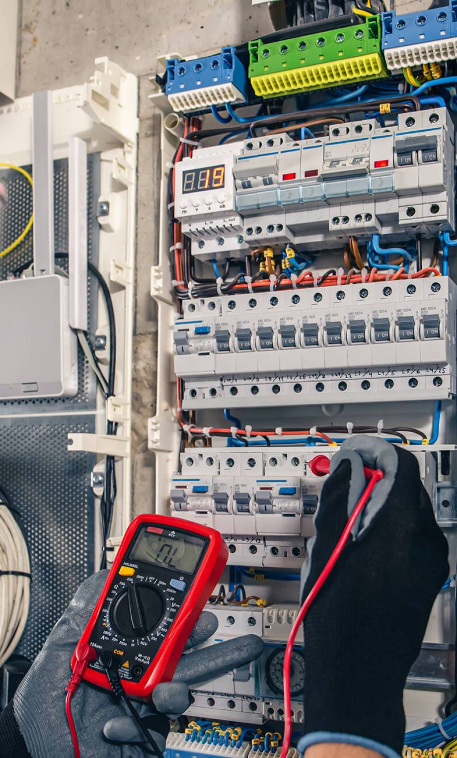 Man, an electrical technician working in a switchboard with fuses. Installation and connection of electrical equipment. Professional uses a tablet.